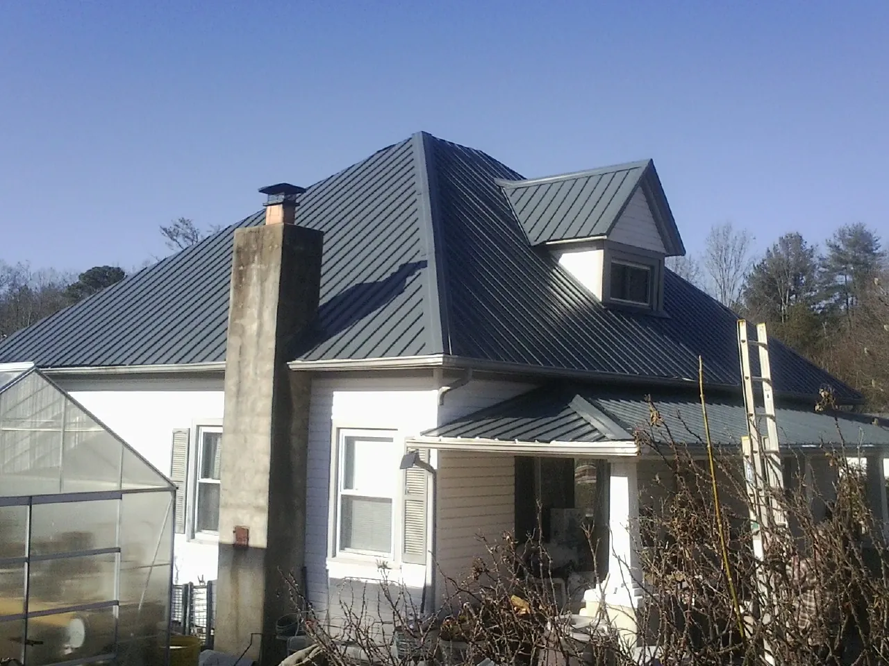Dark blue standing seam metal roof on a white farmhouse with dormer — Slate & Tile Roof Repair by Roofing Brothers in Gilbert