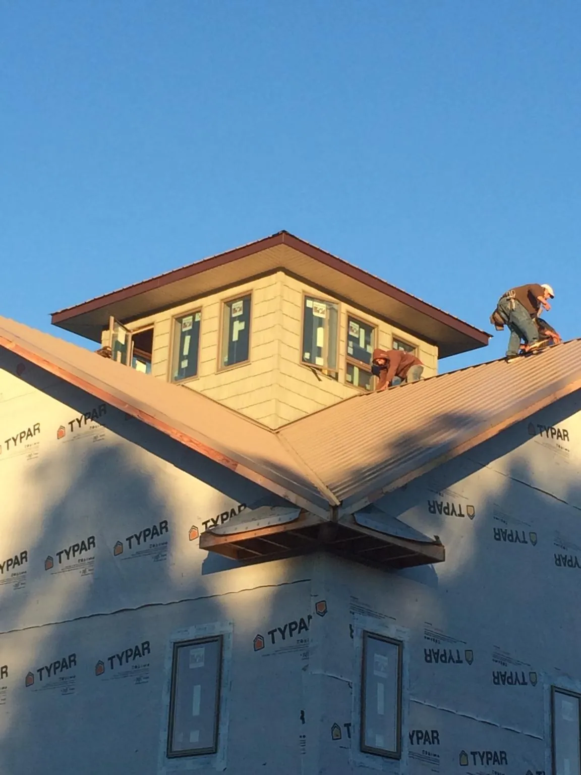 Roofers working around a rooftop cupola on a new metal roof at sunset — Roof Waterproofing in Gilbert by Roofing Brothers